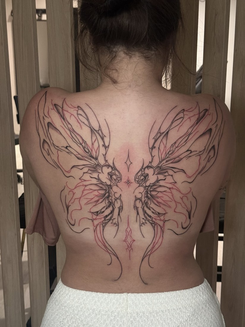 Tatuaje ilustrativo de alas de mariposa en la espalda